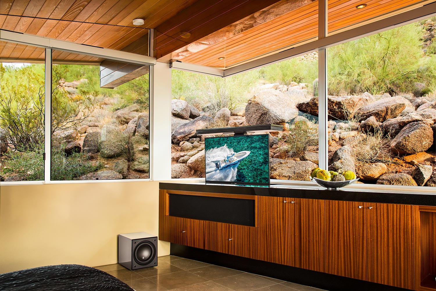Pop-up TV rising from a cabinet with a subwoofer and desert views