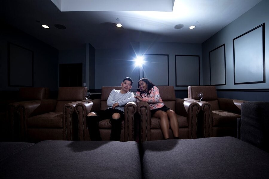 A couple watching a movie in their home theater in luxury home cinema seats.