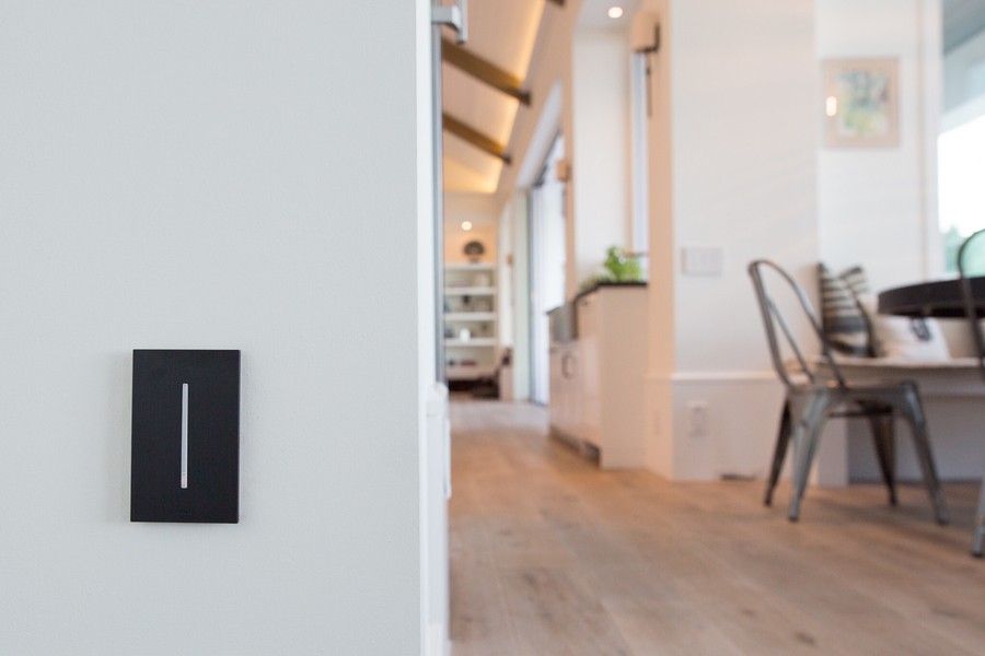 Black Lutron wall panel on the left side with a chair, table, and hallway on the right