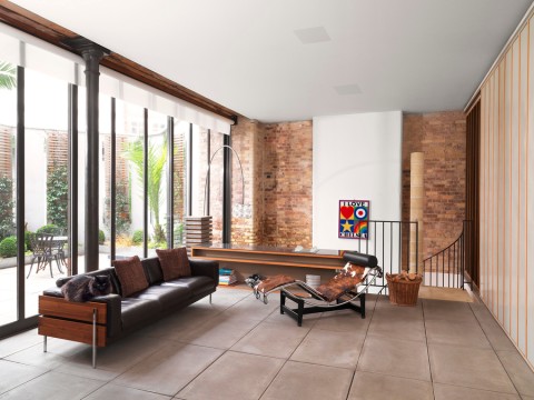 A living room with large windows and architectural speakers on the ceiling.