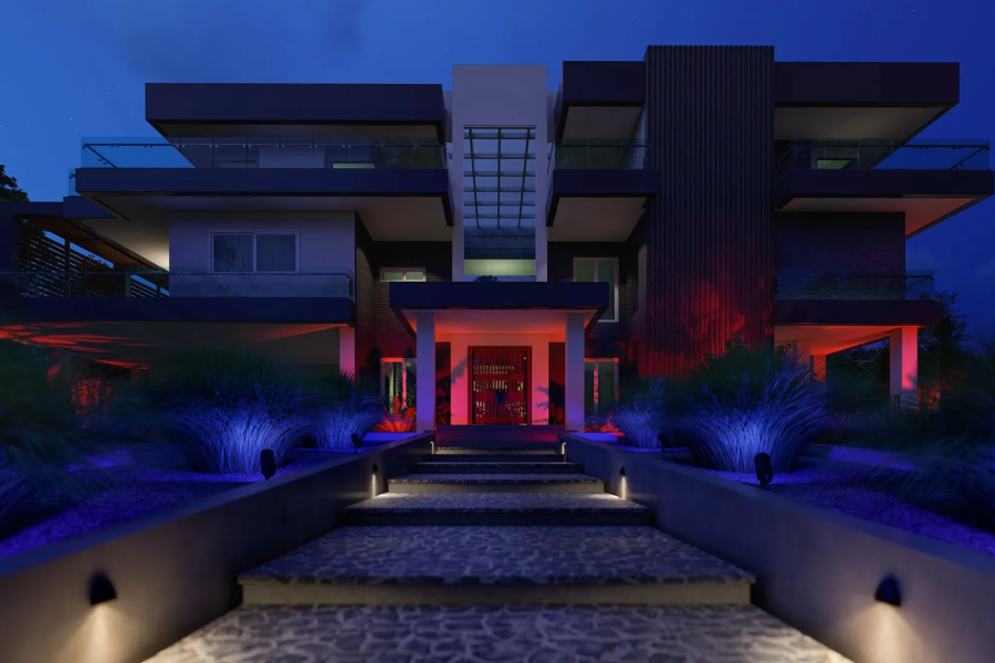 Modern home exterior lit with colored landscape lighting at night
